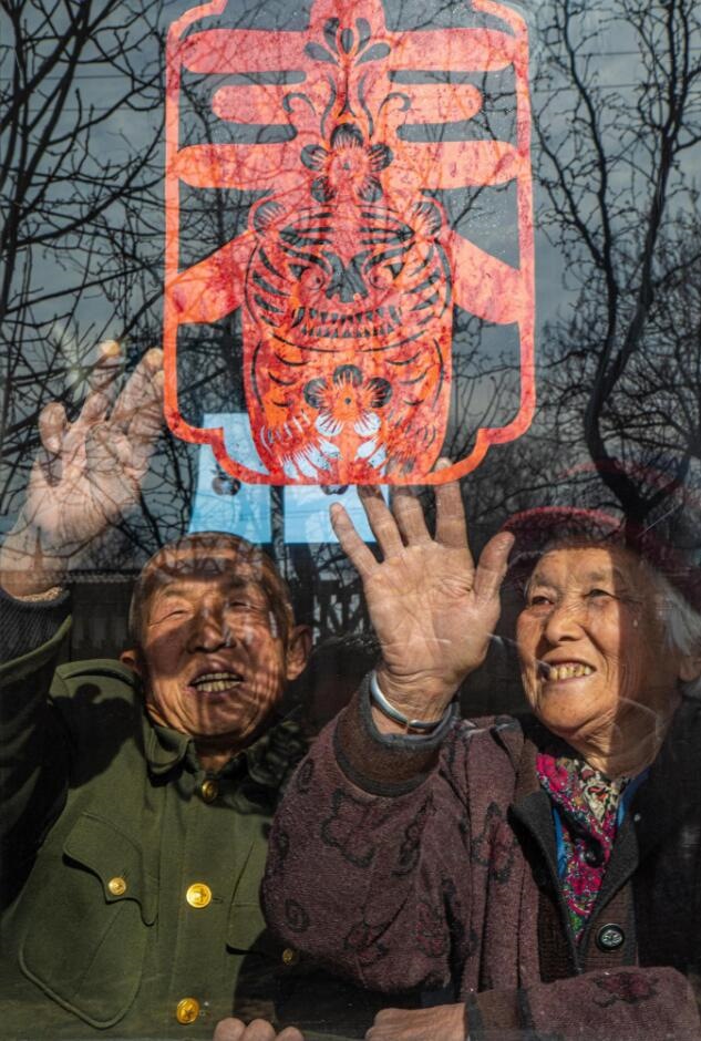 臘月里，霍州市師莊鄉(xiāng)馮南垣村村民師榮光(左)在災(zāi)后重建的新家里貼窗花。(霍州市委宣傳部供圖)