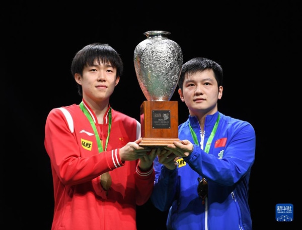 5月27日，樊振東（右）/王楚欽在頒獎儀式上高舉獎杯慶祝。當日，在南非德班進行的2023年世界乒乓球錦標賽男雙決賽中，中國組合樊振東/王楚欽以3比0戰(zhàn)勝韓國組合張禹珍/林鐘勛，奪得冠軍。新華社記者 李亞輝攝