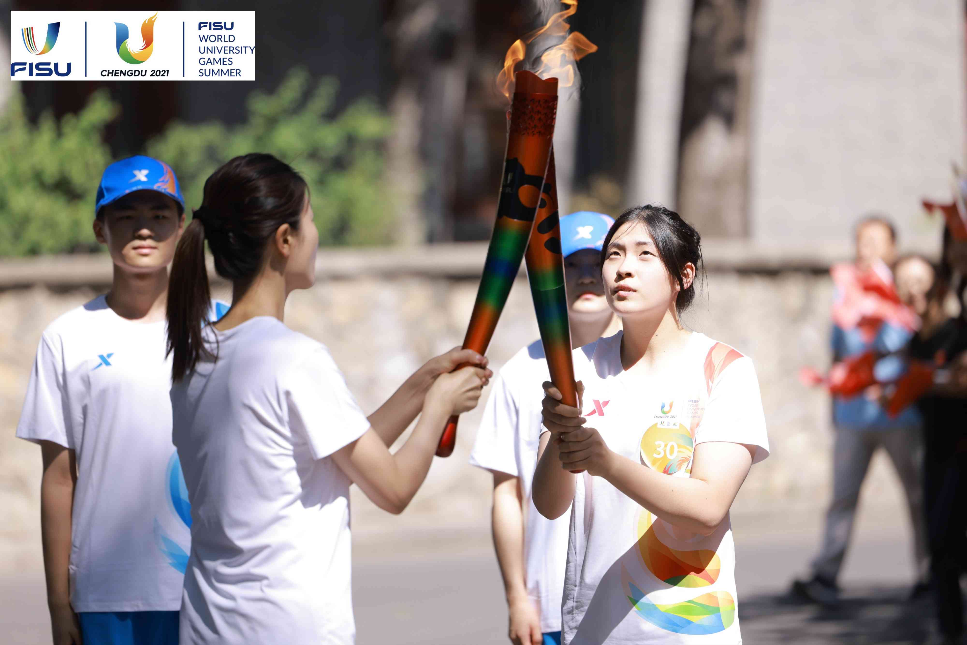 兩名大運(yùn)會(huì)火炬手進(jìn)行火炬?zhèn)鬟f。 圖片來源：成都大運(yùn)會(huì)執(zhí)委會(huì)供圖