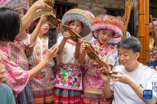 7月29日，在重慶市綦江區(qū)安穩(wěn)鎮(zhèn)，當(dāng)?shù)鼐用裨凇懊缂曳蚬?jié)”上用傳統(tǒng)習(xí)俗向游客表達(dá)祝福。新華社記者 唐奕 攝