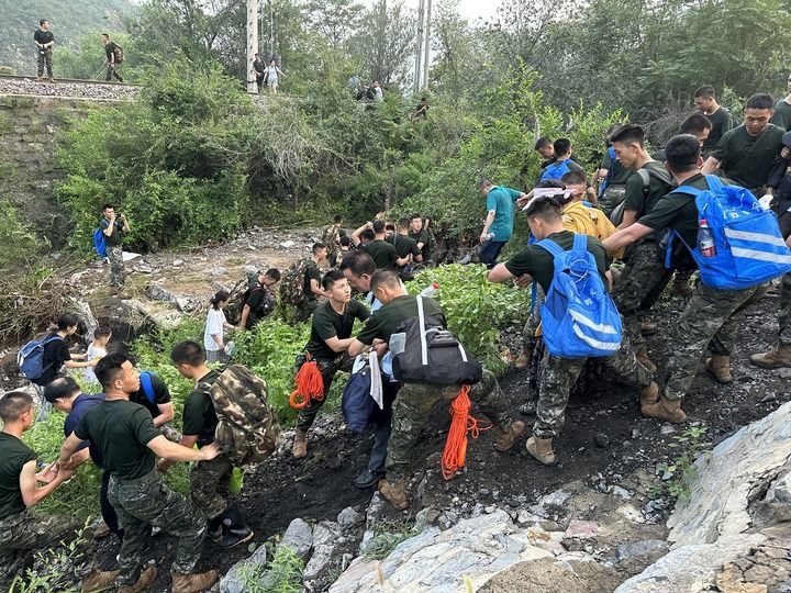 8月2日，Z180次受困列車的旅客在武警北京總隊(duì)機(jī)動(dòng)第三支隊(duì)官兵的幫助下徒步前往轉(zhuǎn)運(yùn)客車（手機(jī)照片）。新華社記者 王艷剛 攝