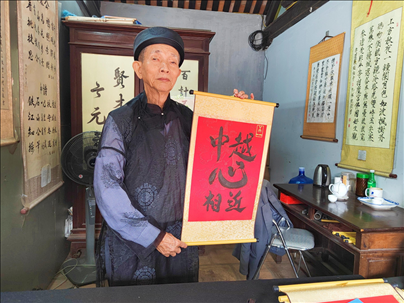 越南首都河內文廟內，阮明珠展示“中越心相近”書法作品。
