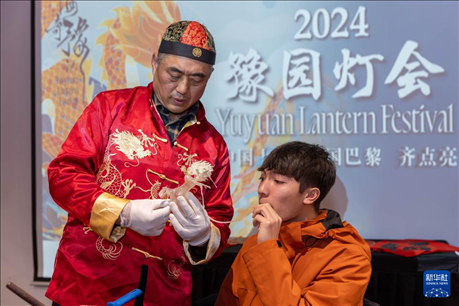1月28日，在上海豫園舉行的民俗活動(dòng)上，美國(guó)馬斯卡廷中學(xué)學(xué)生在非遺傳承人的指導(dǎo)下吹糖偶。 新華社記者 王翔 攝