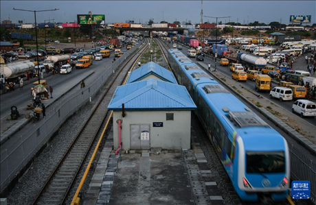 3月4日，在尼日利亞拉各斯，一列輕軌藍線列車行駛至公路交通擁堵路段附近。新華社記者 韓旭 攝