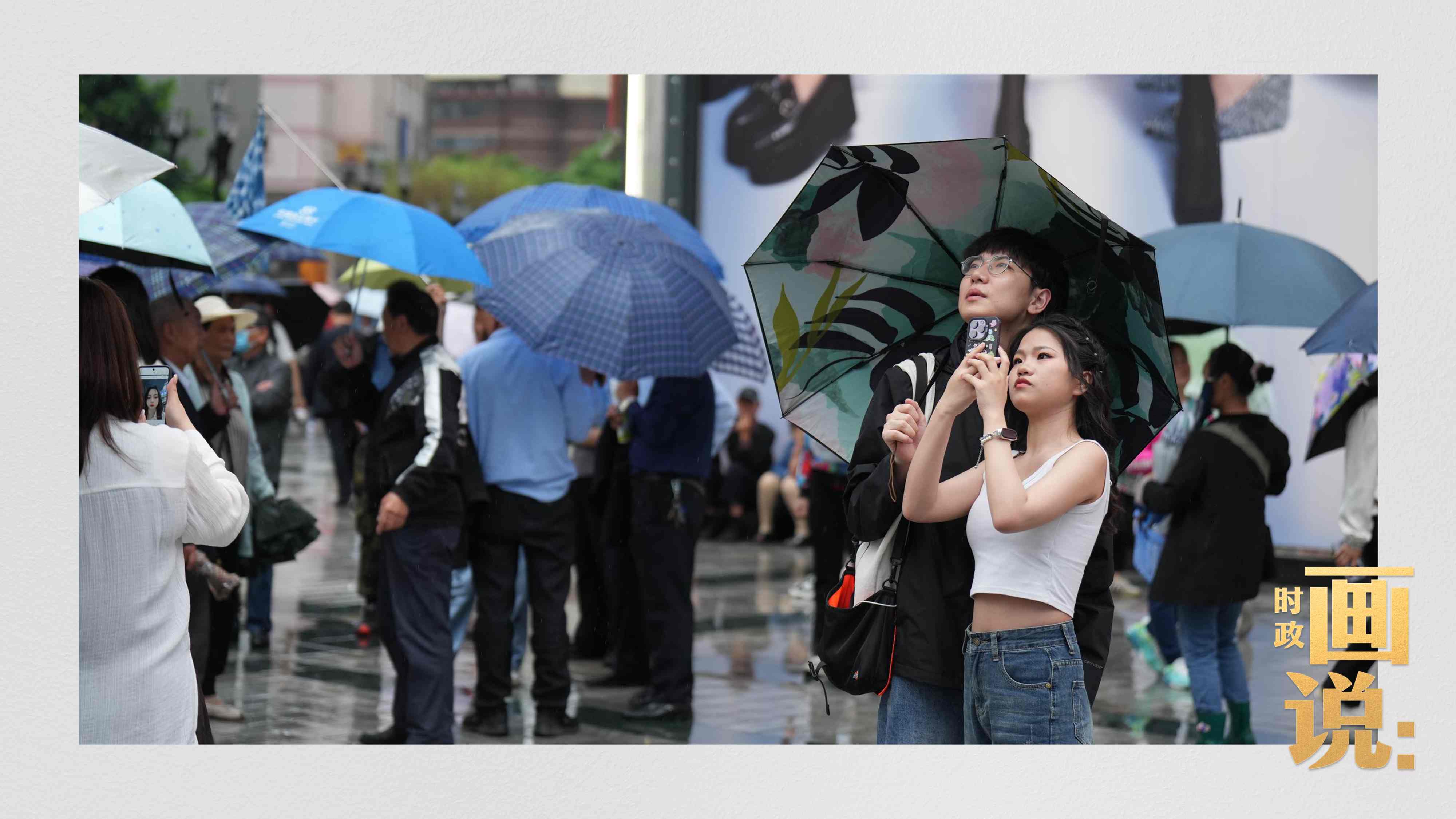 △細(xì)雨中的解放碑步行街，騎在父親肩膀的小女孩好奇張望。