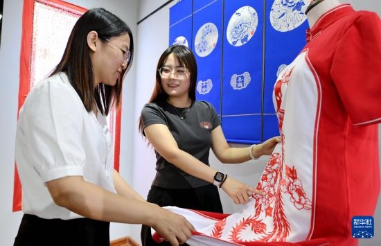5月31日，在衡水市阜城縣一家剪紙工作室，游客在觀賞帶有剪紙元素的旗袍。