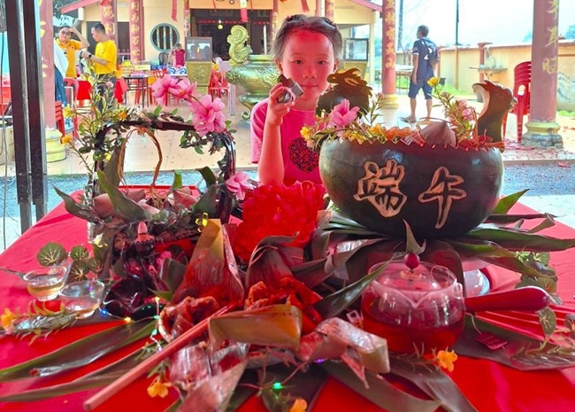小朋友展示學(xué)裹粽子的成品照。組委會供圖