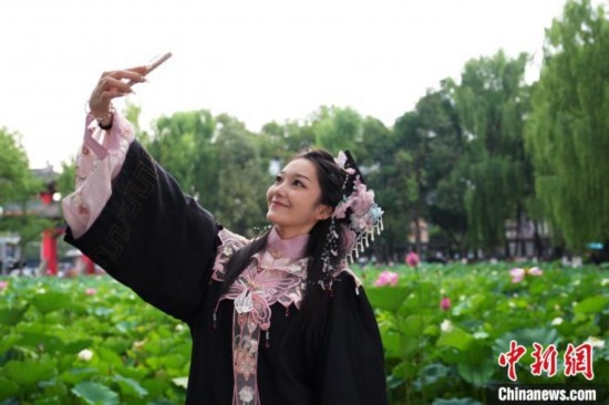 6月19日，時(shí)值一年畢業(yè)季，四川大學(xué)望江校區(qū)荷花池里的荷花盛開(kāi)，成為了畢業(yè)生們的打卡圣地，吸引了眾多畢業(yè)生拍照留念。圖為畢業(yè)生在荷花池邊拍照留念。中新社記者 安源 攝