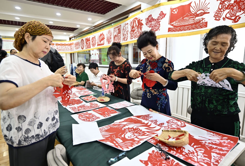 6月19日，長(zhǎng)城花園社區(qū)居民在社區(qū)“才藝堂”制作剪紙。