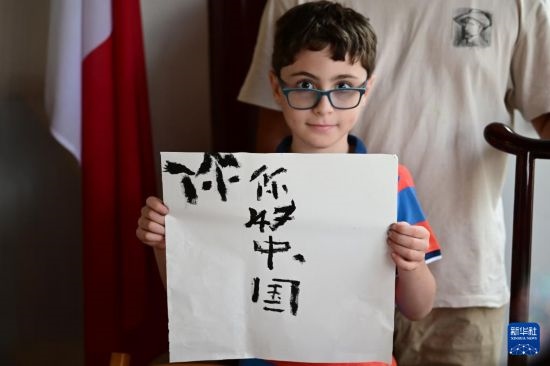7月4日，在馬耳他桑塔露琪亞市的中國古典園林“靜園”，一名男孩展示他的書法作品。新華社發(fā)（喬納森·博格 攝）