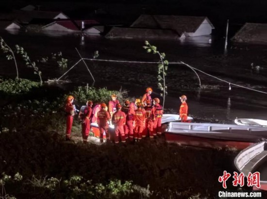  7月6日凌晨3時，在湖南岳陽華容縣團洲垸洞庭湖一線堤防，救援人員剛剛完成一次救援任務(wù)，遠處是被淹的民房。中新社記者 白祖偕 攝