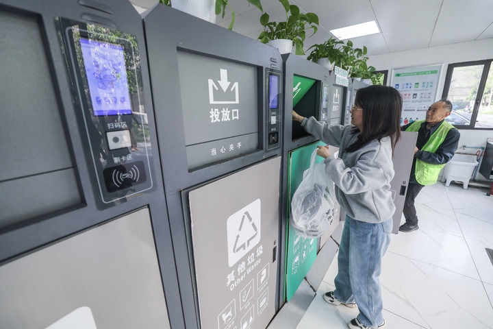2024年4月10日，在浙江省湖州市吳興區(qū)飛英街道新華府小區(qū)內，居民在垃圾分類智能系統(tǒng)的指導下進行垃圾分類投放，居民的投放情況將實時匯總到智慧服務平臺，會有相應的積分獎勵。新華社記者 徐昱 攝