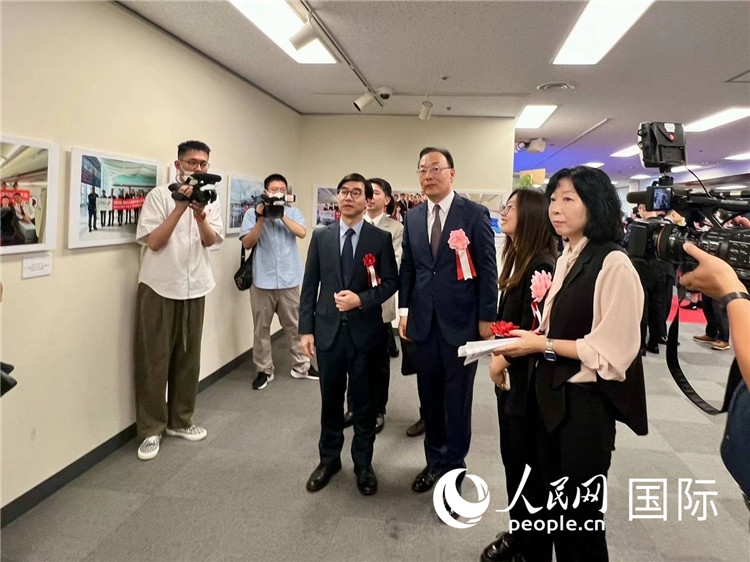 中國國際航空日韓地區(qū)支社支社長馮力為中國駐日本大使館臨時(shí)代辦施泳等嘉賓介紹展出圖片。人民網(wǎng) 許可攝