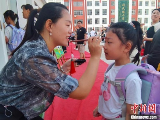 圖為衡水市利民路小學(xué)，老師為學(xué)生點朱砂痣，寓意開啟智慧。張松 攝