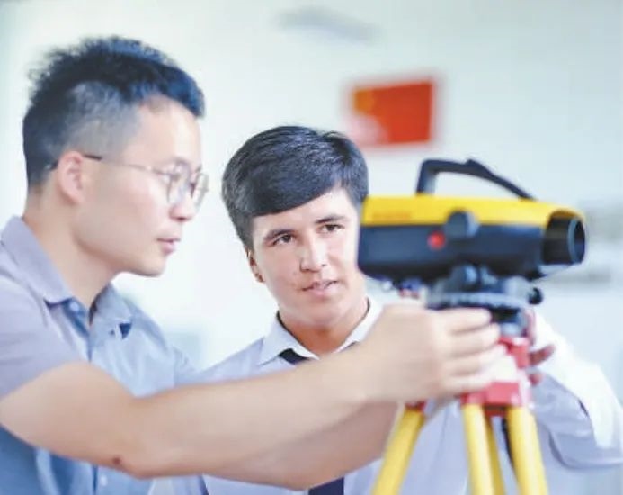 在塔吉克斯坦首都杜尚別的魯班工坊，來自天津城市建設管理職業(yè)技術(shù)學院的老師（左）為當?shù)貙W生提供指導。新華社記者 鄭開君 攝