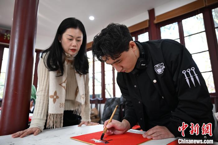 1月20日，外籍留學(xué)生在西泠印社社員李硯指導(dǎo)下寫福。當(dāng)日，來自巴西、馬來西亞、加納、哈薩克斯坦的外籍留學(xué)生在浙江杭州西泠印社體驗(yàn)福貼、春聯(lián)和篆刻，感受古老的中國傳統(tǒng)文化。中新社記者 王剛 攝