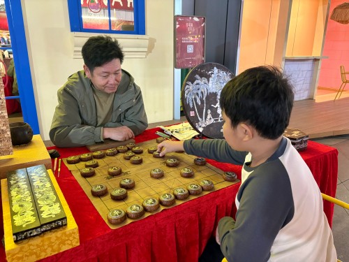 柯秋楓與市民下椰雕象棋。人民網(wǎng) 陳葉欣攝